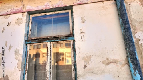 View of the weathered facade of an old house. View of the old facade of the house, its windows and gates. Concept of real estate agencies, reconstruction in the construction industry. Slow motion.