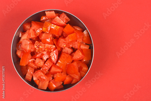 Fotografie A close-up, overhead studio shot shows diced red tomatoes filling a metal bowl o