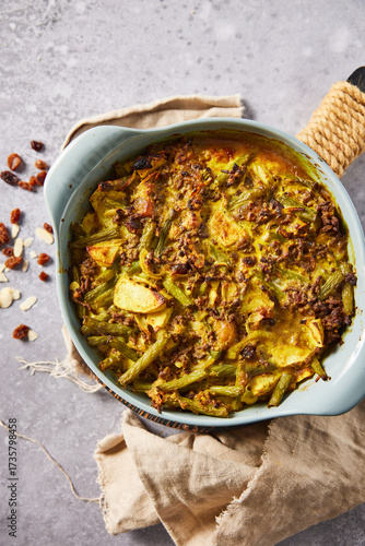Traditional South African bobotie served with yellow rice, chutney, raisins, and almonds. Overhead view of a spiced ground meat and vegetable casserole, a classic Cape Malay dish.