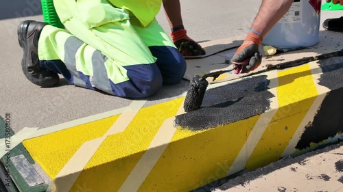 Painting safety stripes on railway platforms. Marking railway platforms with black paint. Concept of color-coded safety marking.