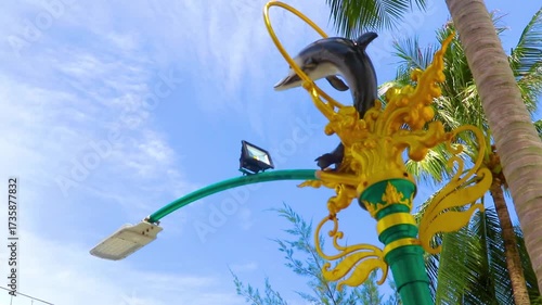 Golden green white street lantern with ornate dolphin figure in Thailand.