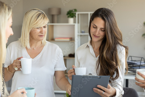 Two women working together at a desk with charts and documents