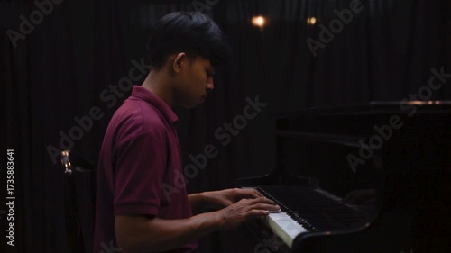Young Man Playing Grand Piano on Stage Under Dramatic Lighting Music Concert or Recital Scene