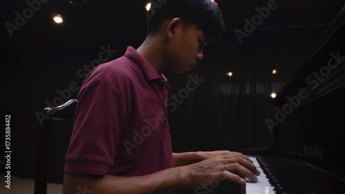 Young Man Playing Grand Piano on Stage Under Dramatic Lighting Music Concert or Recital Scene