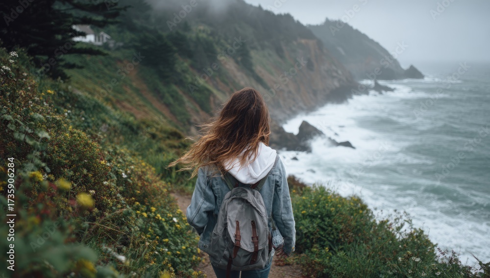 Naklejka premium Woman with backpack walking on a coastal trail overlooking the ocean.