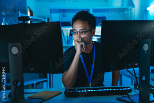 Software engineer analyzing programming language code, focusing on cybersecurity, IT systems, and digital data security in dark office.