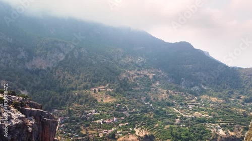 aerial or panoramic footage capturing the stunning natural beauty of Kelebekler Vadisi Butterfly Valley and the majestic Babadag mountains in Fethiye, Turkey. This footage showcases the lush green slo