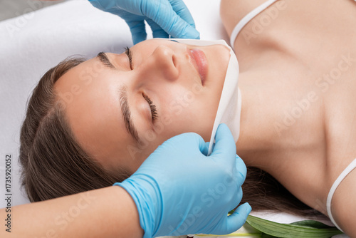 Slika na platnu A cosmetologist makes a fat-burning mask for a double chin
