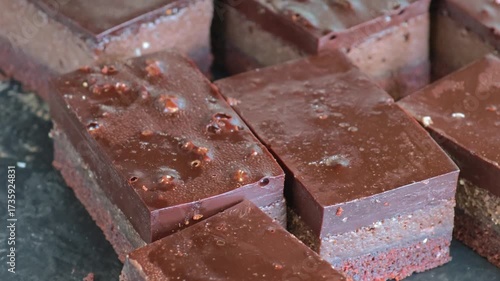 Freshly baked slices of chocolate brownies on display on a market stall.