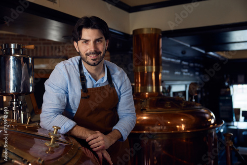 Confident brewer man wearing an apron is diligently working in a brewery setting