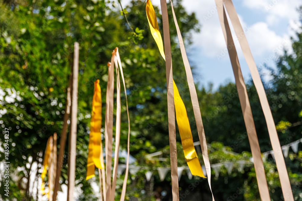 Fototapeta premium Colorful Ribbons Decorate a Lively Outdoor Setting with Green Trees and Bright Blue Sky, Creating a Festive Atmosphere Perfect for Celebrations and Joyful Gatherings in Nature
