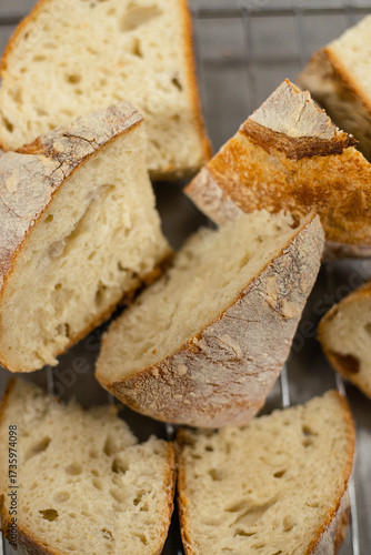 Close up view of sliced artisan sourdough bread pieces placed on a cooling rack in a bakery kitchen.