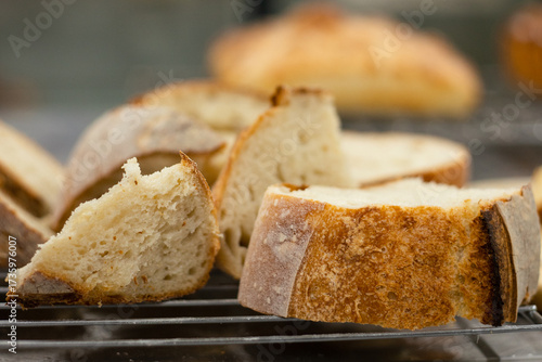 Close up view of sliced artisan sourdough bread pieces placed on a cooling rack in a bakery kitchen.