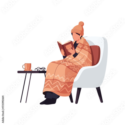 Person wrapped in blanket, wearing hat, reading book while sitting in chair with cup tea and glasses on small table