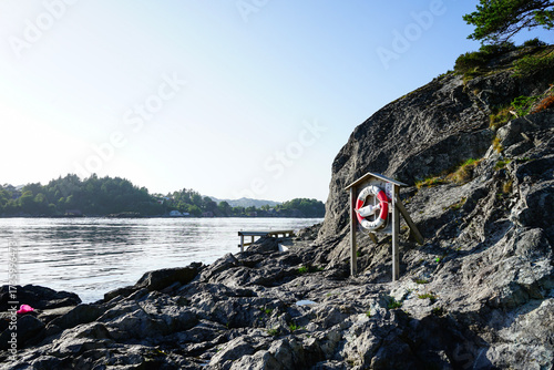 Lifebuoy station on rocky shore by the water. Norway.