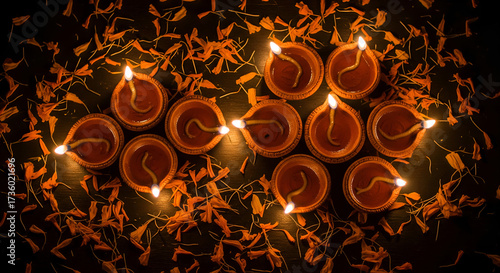 Top-down view of a luminous curve of traditional clay diyas glowing amidst scattered marigold petals for the Diwali festival.