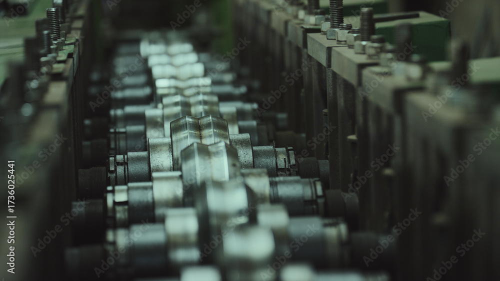 Obraz premium Metal rollers in a manufacturing facility precisely shaping and bending sheet metal on an assembly line, representing industrial production and precision engineering processes