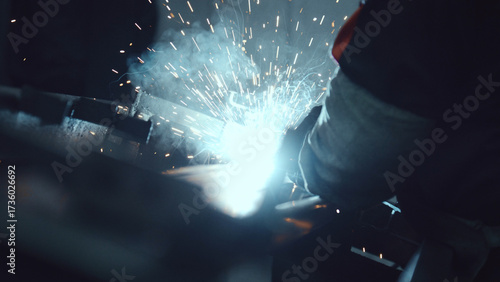 Canvas Print Welder in an industrial workshop producing bright arc light, sparks and smoke wh