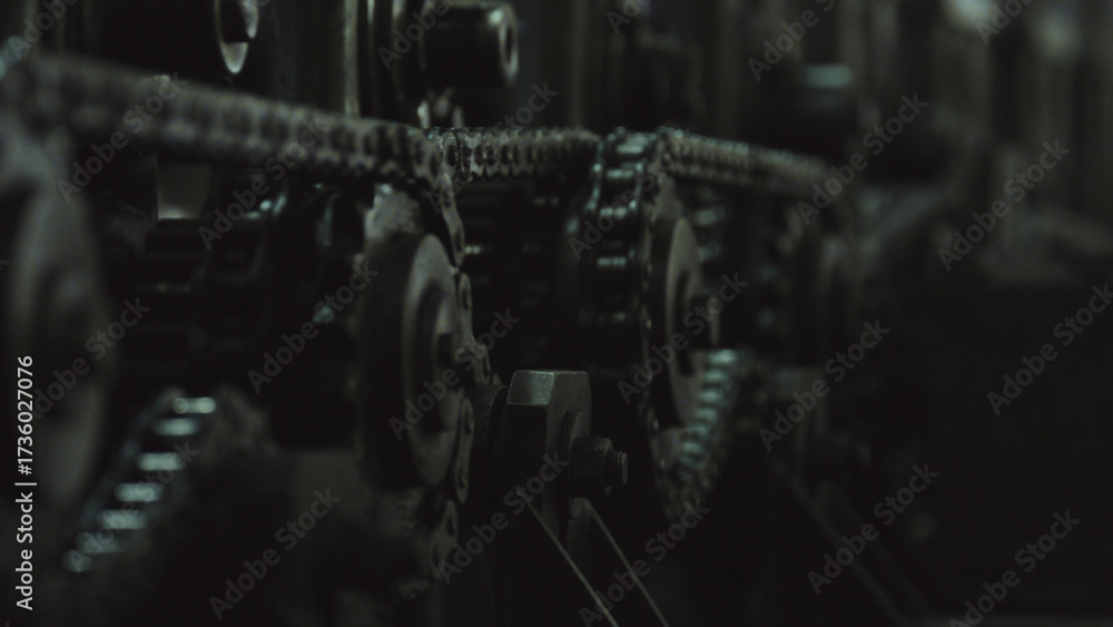 Fototapeta premium Industrial equipment working, featuring a detailed view of interlocking metal chains and gear sprockets demonstrating power transmission and continuous motion in a factory setting