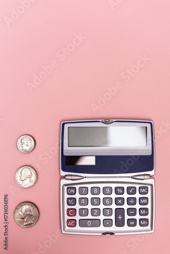 close-up of a compact calculator and small piles of quarters, nickels, and dimes against a pink background in a vertical orientation with copy space available