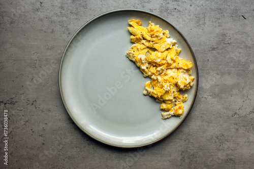 freshly scrambled eggs on a gray plate centered on a gray textured background