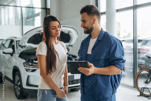 Giving the consultation. Woman customer is in the car repair service station with mechanic