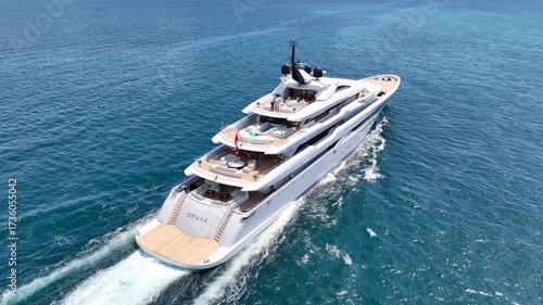 Aerial drone cinematic tracking video of luxury yacht with wooden deck cruising deep blue Aegean Sea, Mykonos island, Cyclades, Greece