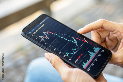 Close-up of Hand Tapping Smartphone Screen to Analyze Bearish Cryptocurrency or Stock Market Graph on a Mobile Trading App
