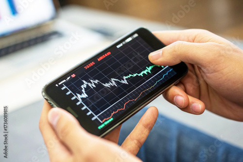 Close-up of Hands Holding Smartphone to Analyze Live Stock Market, Cryptocurrency, or Forex Trading Graph on a Financial App