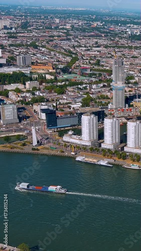 Dynamic 4K vertical aerial video of Rotterdam harbor with cargo ship, modern waterfront architecture, and containers. Stunning drone footage showcasing Dutch port city logistics, ideal for mobile.