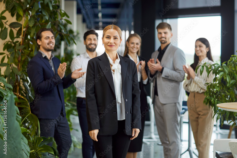 Obraz premium Portrait of a happy and smiling businesswoman in an office surrounded by team business people during meeting. Teamwork, success, professional interaction, and a collaborative environment.