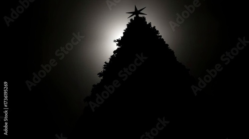 Low angle silhouette Christmas tree against a bright light source, viewed from below, dramatic