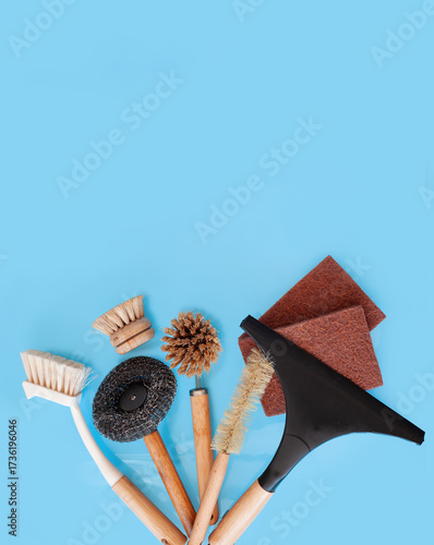 Top view cleaning supplies, bamboo brushes and natural sponges, zero waste household concept on a blue background