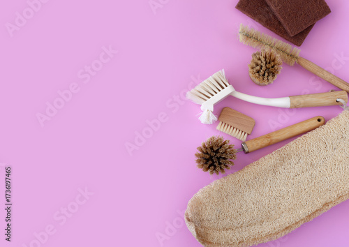 Top view cleaning supplies, bamboo brushes and natural sponges, zero waste household concept on a pink background