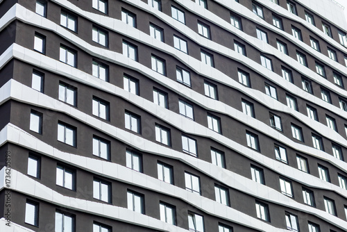 Fotografie A modern residential complex with a wave-shaped façade, finished in dark tones with white accents