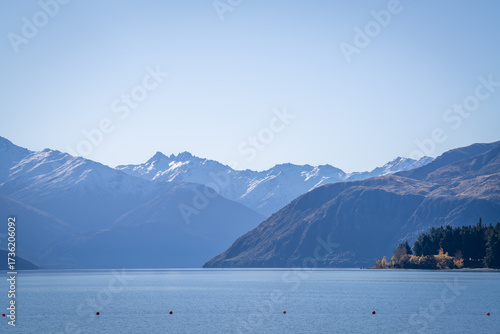 yellow colorful autumn leaves tree along wanaka lake with snow cap mountain range background in sunny day is very beautiful landscape view South Island New Zealand