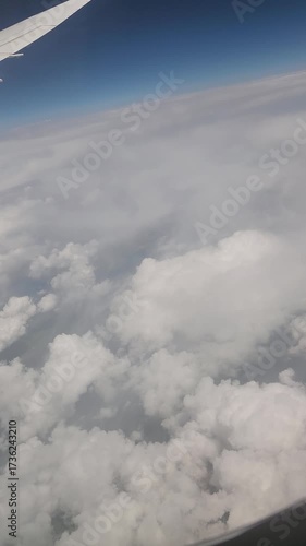 view of wing from plane window. Airplane flying above clouds. Airplane fly over snowy mountain hills. vertical video