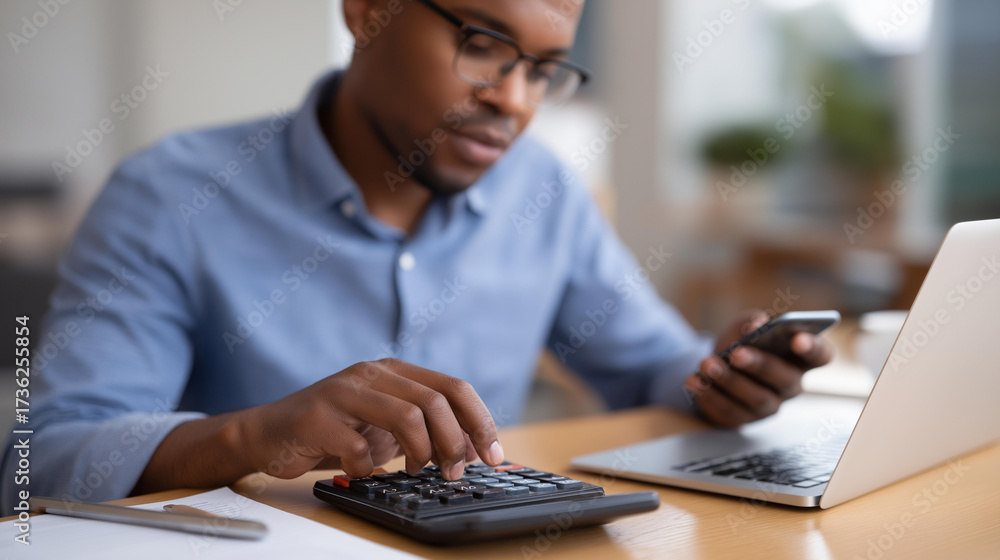 Fototapeta premium Business manager calculating financial numbers at organized desk with laptop and smartphone in office tracking budget and revenue data calculator accounting manager calculating