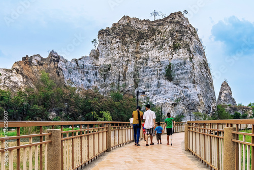 Back view of lovely family enjoy walking on the walkway with beautiful nature scenic landscape with stone mountain range also call Snake Mountain at Khao Ngu Stone Park in Thailand. Amazing nature.