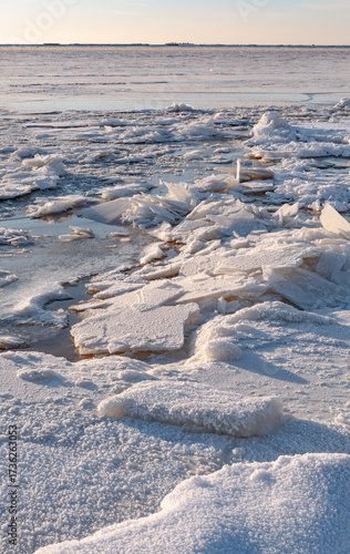 winter seascape showing frozen sea ice with cracked sheets and textured snow on the surface. Natural icy patterns and frozen water landscape in cold climate.