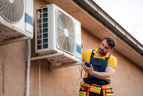 Technician performing maintenance on outdoor air conditioning unit at residential building