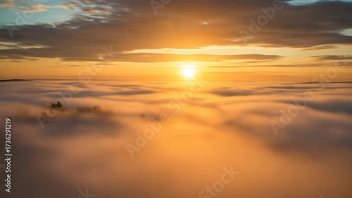 Golden sunrise over a misty landscape with clouds in the foreground, the camera slides over the clouds  