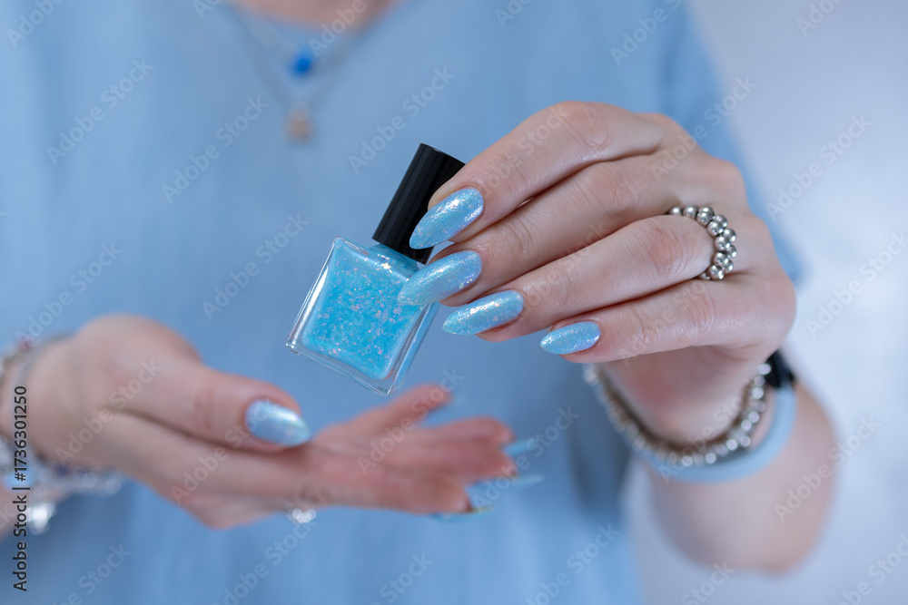 Obraz premium Woman's beautiful hand with long nails and light baby blue manicure