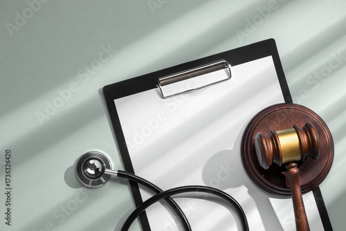 Принти на полотні Judge gavel with stethoscope on clipboard close-up on soft green background with sunlight from the window