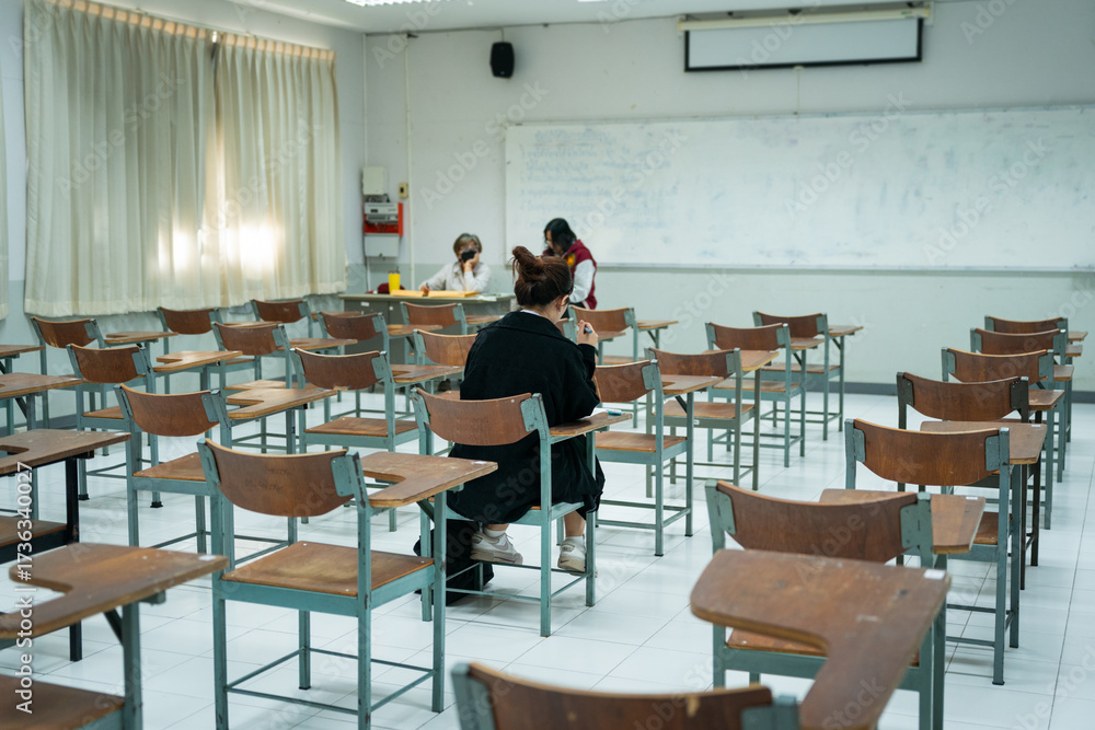 Fototapeta premium Last Student Completing Final Exam in Classroom