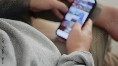 Man using his smartphone to scroll through an Instagram feed, browsing posts and videos. 4K UHD.