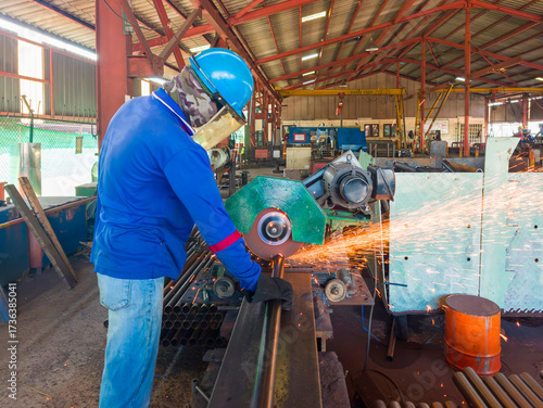 Industrial Worker Cutting Steel Pipe with a CUT-OFF Machine in a Factory, Wearing a Safety Helmet, Gloves, and Protective Gear, Sparks flying from the Cutting Process.