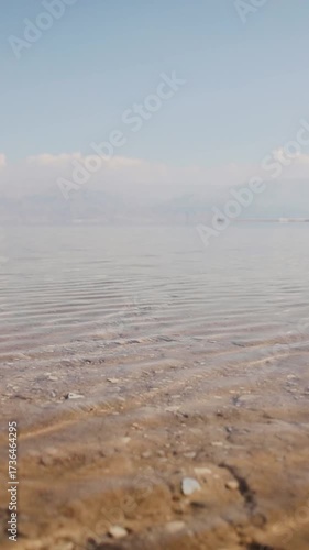 Distant view of sea and beach on a sunny day. Dead sea near Ein Bokek, Israel. Shore of the Dead Sea in calm weather. Vertical video
