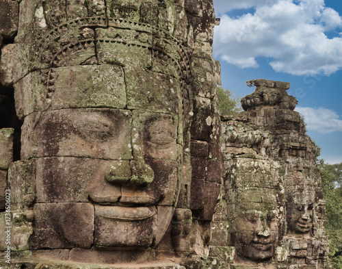 Khmer Smiling Stone Face - A close-up of a weathered, smiling stone face carving on a historic temple at Angkor, with detailed features and textures.