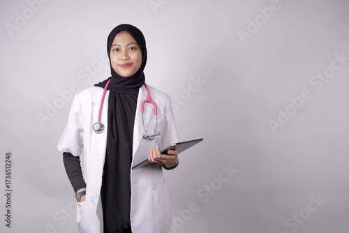 Asian Muslim doctor holding medical records, putting his hands in his lab coat and carrying a stethoscope, against a white background of a medical advertisement.